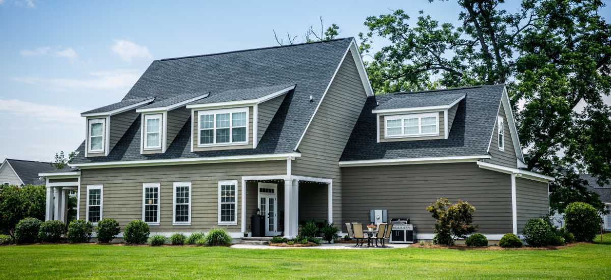Two-story gray house with white trim and a landscaped front lawn