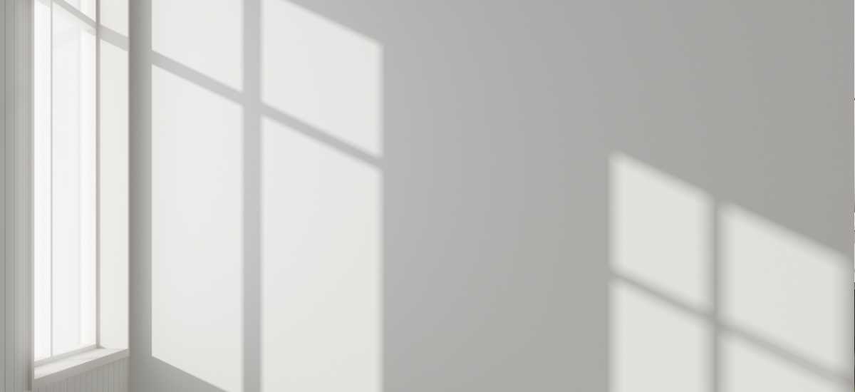 Sunlight and window shadows across a light gray wall